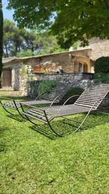 a metal bench sitting in the grass in a yard at Mas la Floreline in Cheval-Blanc