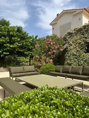 a patio with couches and pink flowers and a building at Maison familiale avec piscine in Aix-en-Provence