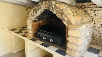 a stone fireplace with a black stove in it at Mazet des Balestiés cœur Luberon 120 m2 6 pers avec piscine in Gargas