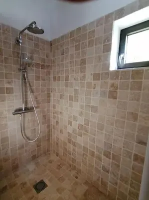 a shower in a tiled bathroom with a window at Le Mazet d'Alexis in Maubec