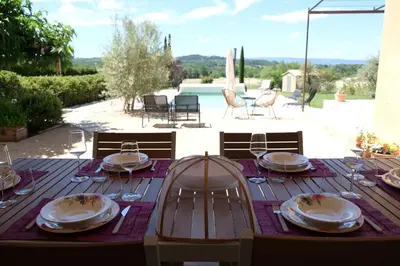 a wooden table with plates and wine glasses on it at Air-conditioned villa with private pool overlooking Roussillon - Luberon - 8 people. in Roussillon