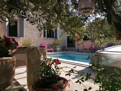 a swimming pool with potted plants next to a house at la bastide aux buis avec piscine in Blauvac
