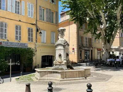 a fountain in the middle of a street with buildings at Bergerie de charme proche Aix en Provence et Lubéron in Rognes
