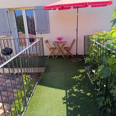a patio with a table and an umbrella at Chez Lucho et carole in La Bastidonne