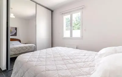 a white bedroom with a bed and a mirror at 2 Bedroom Nice Home In Chateaurenard in Châteaurenard