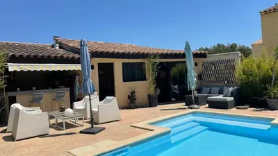 a pool with chairs and umbrellas next to a house at Studio Le Pitchoun in Pernes-les-Fontaines