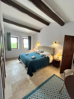 a bedroom with a large bed with a blue blanket at Les Cachots in Roussillon