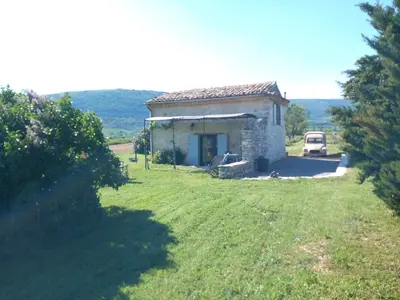 a small stone house in a field with a car at Le grangeon des Hermas in Sault-de-Vaucluse
