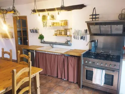 a kitchen with a sink and a stove and a table at Villa face au Mont Ventoux avec bassin in Modène