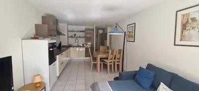 a living room with a blue couch and a kitchen at Appartement, 1 chambre, jardin privatif in Venelles