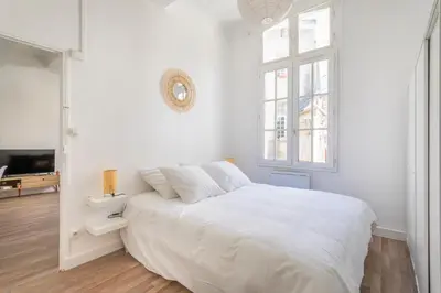 a white bedroom with a large bed and a window at T2 lumineux plein centre à 5 min du Cours Mirabeau confort, wifi, cuisine équipée in Aix-en-Provence