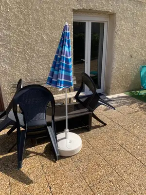 a blue and white umbrella and a chair and a table at Suite avec sauna in Pertuis