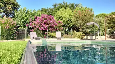 a swimming pool in a yard with pink flowers at Le PEROTIN in Villes-sur-Auzon