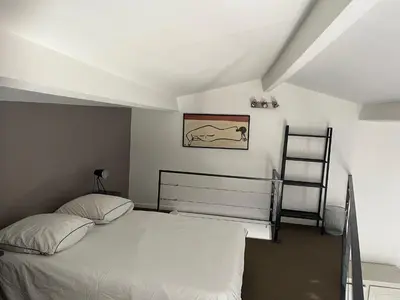 a bedroom with a white bed and a ladder at Le Loft de Roxane Centre historique Aix en Provence in Aix-en-Provence