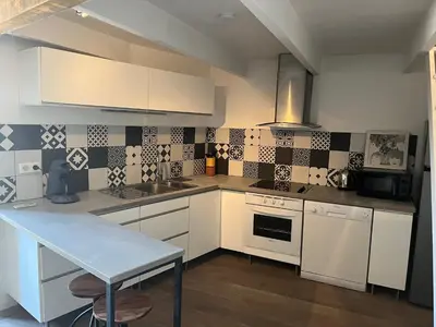 a kitchen with white cabinets and black and white tiles at Le Loft de Roxane Centre historique Aix en Provence in Aix-en-Provence