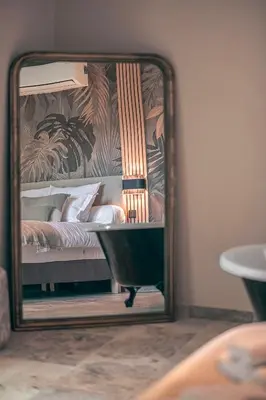a mirror in front of a bed in a room at Les Suites de l'Étang in Cucuron