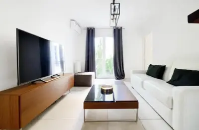 a living room with a white couch and a flat screen tv at La Rotonde - Magnifique Appartement climatisé avec parking in Aix-en-Provence