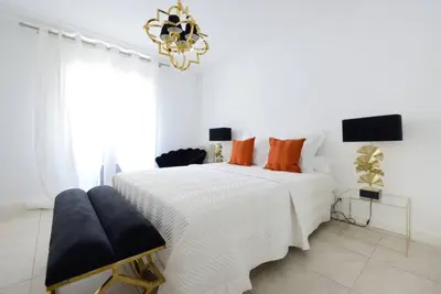 a white bedroom with a large bed and a chandelier at La Rotonde - Magnifique Appartement climatisé avec parking in Aix-en-Provence