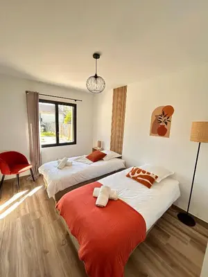 a bedroom with two beds and a red chair at Villa en Provence avec piscine in Mollégès