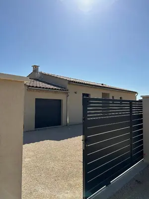 a garage with a black gate in front of a house at Villa en Provence avec piscine in Mollégès