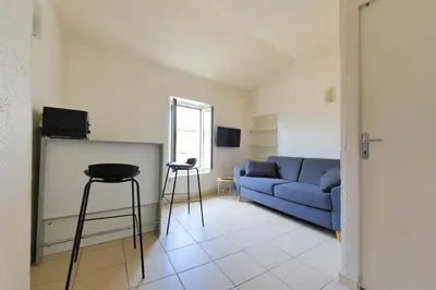 a living room with a blue couch and a table at Studio Lavande in La Fare-les-Oliviers