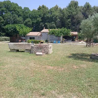 a yard with a stone wall and a house at Maison au coeur du Lubéron in Maubec