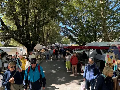 a crowd of people walking down a street at a market at La Bergerie de Chateau Fontvert in Lourmarin