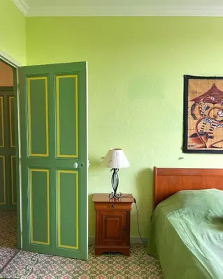 a bedroom with a green door and a table with a lamp at Chambre de 2 personnes dans Mas de Lubéron in Robion en Luberon
