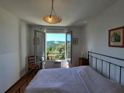 a bedroom with a bed and a large window at Maison de vacances avec piscine privative, Oustau des Oliviers vue dominante Colorado provençal in Rustrel