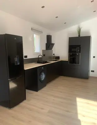 a room with a kitchen with black cabinets and appliances at Gîte Lavande Luberon in Saint-Saturnin-les-Apt