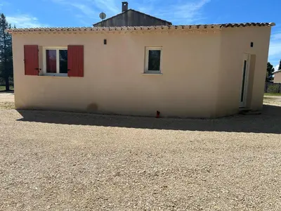 a small house with red doors and a gravel driveway at Gîte Lavande Luberon in Saint-Saturnin-les-Apt