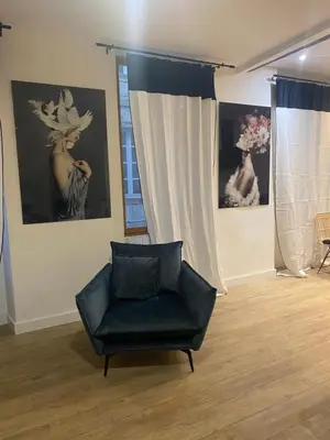 a black chair in a room with paintings on the wall at Bel appartement en plein cœur de Carpentras in Carpentras