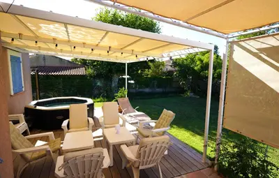 a patio with chairs and tables under a canopy at Anna et Jean-Paul in LʼIsle-sur-la-Sorgue