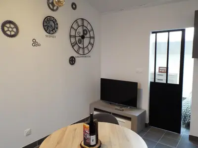 a living room with a tv and clocks on the wall at Valentins cottage Moulin de Tartay Avignon in Avignon
