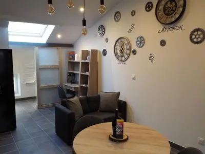 a room with a table and a couch and clocks on the wall at Valentins cottage Moulin de Tartay Avignon in Avignon