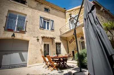 a patio with a table and an umbrella in front of a house at Valentins cottage Moulin de Tartay Avignon in Avignon