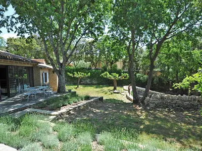 a backyard with a table and chairs under some trees at Le Chant des Bories in Gordes