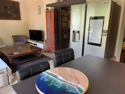 a living room with a table and a room with a tv at Charmante Maison au cœur du village in Rustrel