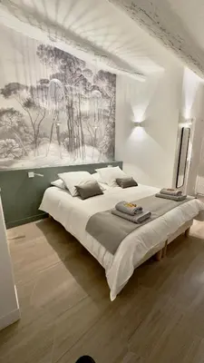 a bedroom with a large bed with a painting on the wall at Centre Historique Appartement Climatisé avec terrasse in Aix-en-Provence