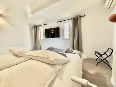a white room with two beds and a chair at Centre Historique Appartement Climatisé avec terrasse in Aix-en-Provence