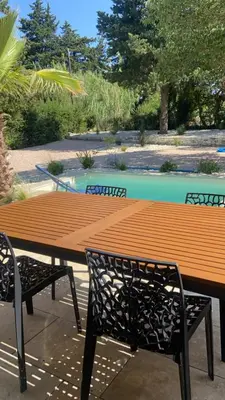 a wooden table and two chairs sitting next to a pool at Maison avec piscine et jacuzzi proche de la rivière idéale pour un séjour détente in Le Thor