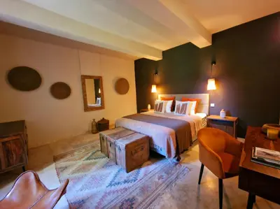 a bedroom with a bed and a chair and a table at Bastide des 7 Sœurs in Roussillon