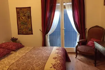 a bedroom with a bed and a chair and a window at La maison Danna in Lauris