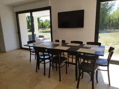 a dining room with a table and chairs and a flat screen tv at Mas en Provence in Le Thor
