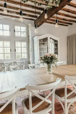 a dining room with a large wooden table and white chairs at Le Bas Château Provence Luberon in Saint-Michel-lʼObservatoire