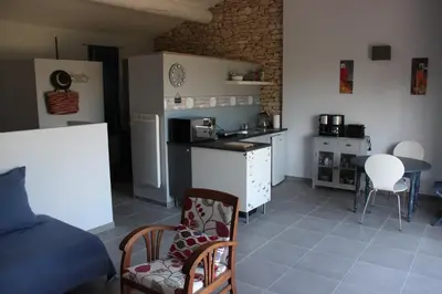 a living room with a kitchen and a table at La cigale bleue in Gordes