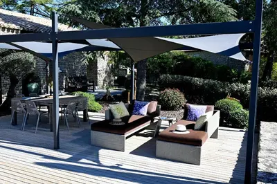 a patio with chairs and an umbrella and a table at La Suite Gordes in Gordes
