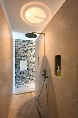 a bathroom with a shower with a stone wall at La Suite Gordes in Gordes