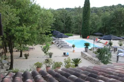a view of a swimming pool with umbrellas at Le Gîte du Hameau Fleur de Pierres in Gordes