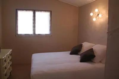 a bedroom with a white bed and a window at Le Gîte du Hameau Fleur de Pierres in Gordes
